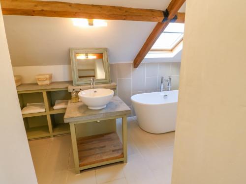 a bathroom with a sink and a tub and a mirror at The Stable, Sedbury Park Farm in Gilling