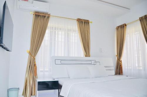 a white bedroom with two beds and curtains at Jama Residence in Abuja