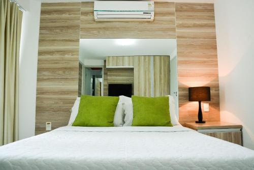 a bedroom with a white bed with green pillows at KING's FLAT HOTEL NATAL in Natal
