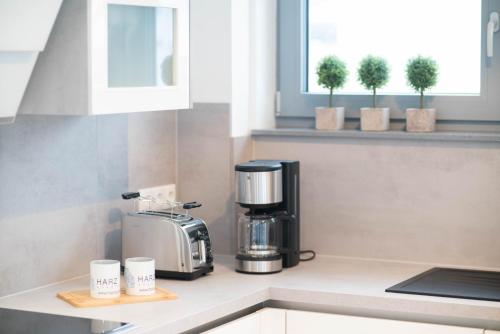 a coffee maker and cups on a kitchen counter at Lindenberg Apartments in Wernigerode