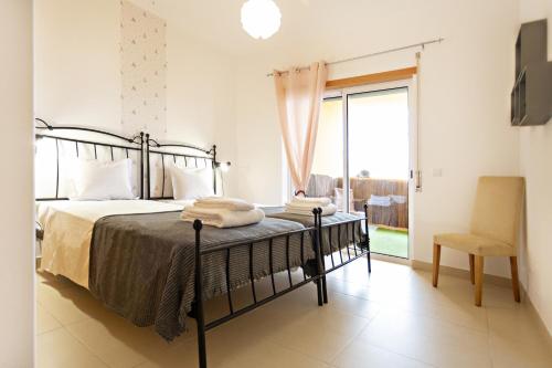 a bedroom with a bed and a chair and a window at Fleming Apartment in Tavira