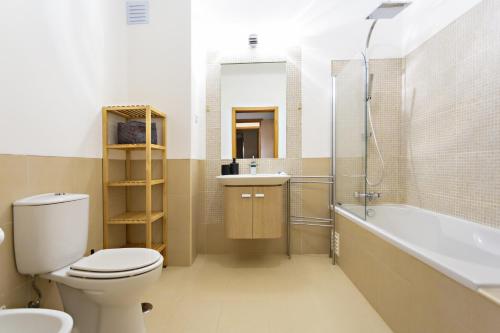 a bathroom with a toilet and a tub and a sink at Fleming Apartment in Tavira