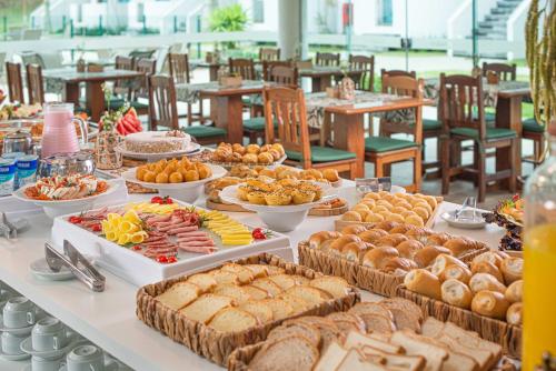 un buffet avec de nombreux types d'aliments différents sur une table dans l'établissement Makkai Resort Hotel Bombinhas, à Bombinhas