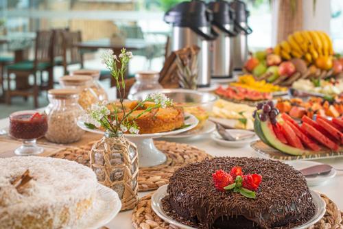 a table topped with cakes and plates of food at Makkai Resort Bombinhas in Bombinhas