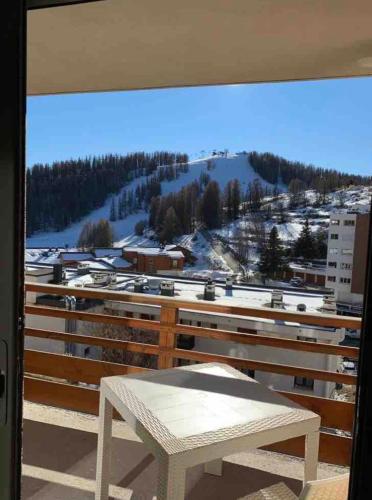 a white bench on a balcony with a snow covered mountain at Magnifique Appartement Valberg in Péone