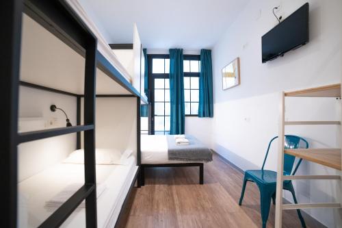 a small room with a bed and a tv at Koba Hostel in Donostia-San Sebastián
