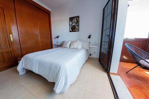 a bedroom with a white bed and a sliding glass door at Casa Paula, Costa Teguise in Costa Teguise