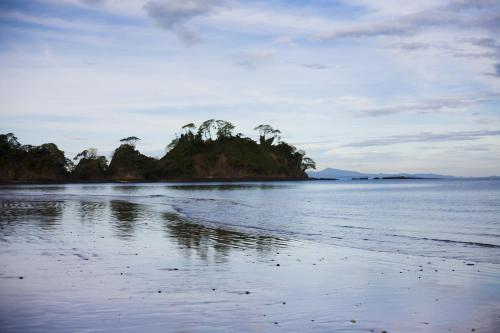 an island in the water with trees on a beach at Hotel Arenas en Punta Leona in Jacó