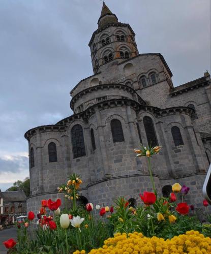 an old church with flowers in front of it at Iris, Gîte Saint Antoine, Orcival, entre Sancy et Volcans d'Auvergne in Orcival