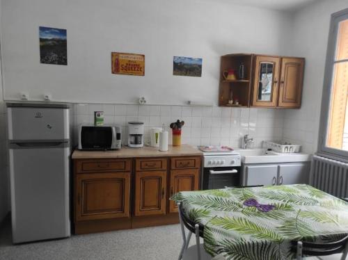 a kitchen with wooden cabinets and a table with a microwave at Iris, Gîte Saint Antoine, Orcival, entre Sancy et Volcans d'Auvergne in Orcival