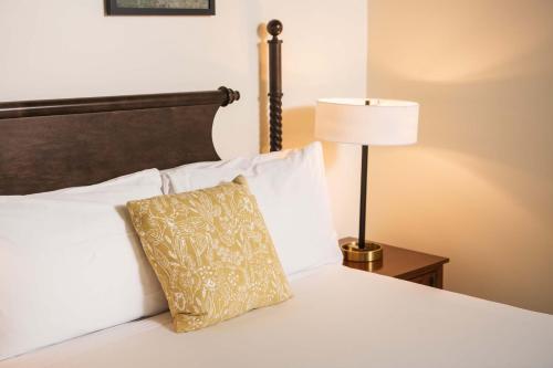 a white bed with a pillow and a lamp at The Whitlock by The Lenox Collection in Lenox