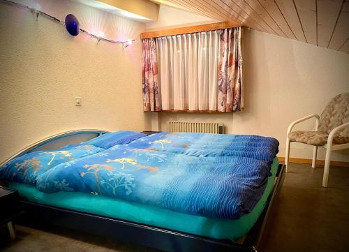 ein Bett mit blauer Decke in einem Schlafzimmer in der Unterkunft Haus Antares in Saas-Almagell