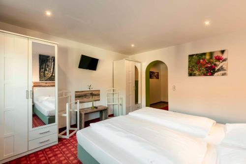 a bedroom with a large white bed and a television at Landhotel GrünWies -Bonsai-Wellness Garni in Lohberg