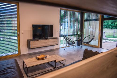 sala de estar con TV de pantalla plana y mesa en Residence Novak Bohinj, en Bohinj
