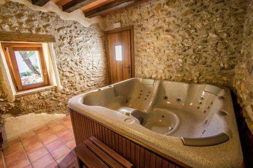 Bisbal del PenedèsにあるCatalunya Casas Captivating Villa in the Vineyard close to Sitgesの窓付きの石造りのバスルーム(大きなバスタブ付)