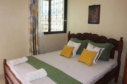 1 dormitorio con 1 cama con almohadas amarillas y verdes en Stylish Cozy Home, en Mombasa