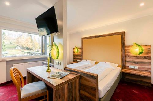 a bedroom with a bed and a desk with a television at Landhotel GrünWies -Bonsai-Wellness Garni in Lohberg
