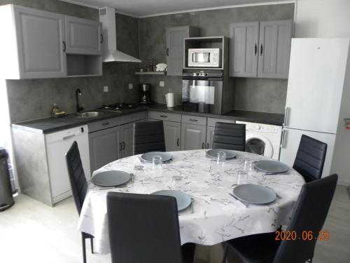 eine Küche mit einem Tisch mit Stühlen und eine Küche mit weißen Schränken in der Unterkunft gîte du puits in Laives