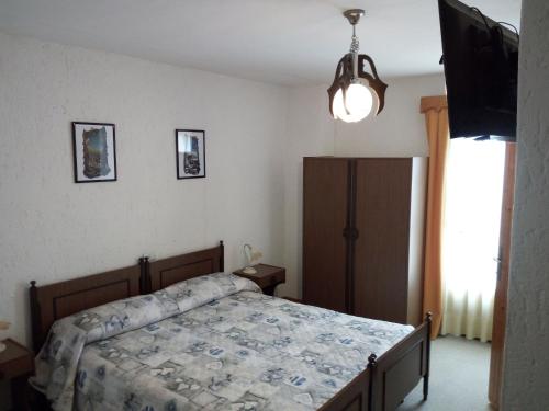 エーネゴにあるAlbergo Al Pinoのベッドルーム(ベッド1台、薄型テレビ付)