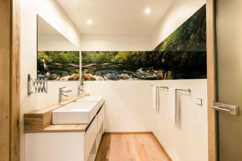 Baño con 2 lavabos y una pintura en la pared en Landhotel GrünWies -Bonsai-Wellness Garni, en Lohberg