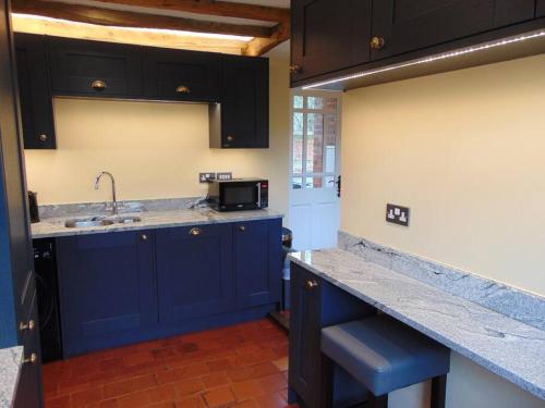 a kitchen with blue cabinets and a sink at Beautifully appointed & cosy self contained annexe 