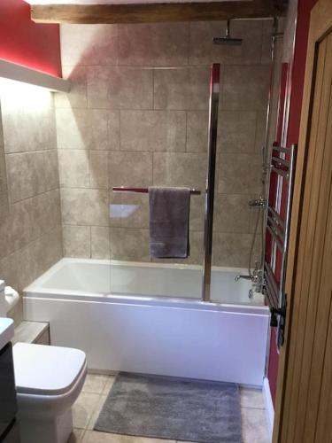 a bathroom with a bath tub and a toilet at Beautifully appointed & cosy self contained annexe in Walsham le Willows