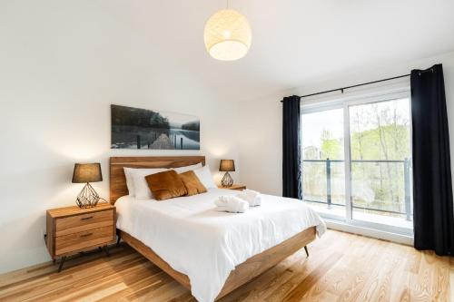 um quarto com uma cama e uma grande janela em Le Memph Aigle spacious comfortable condo cottage eco friendly 3 bedrooms - hot tub & pool Memphrémagog Lake em Magog-Orford