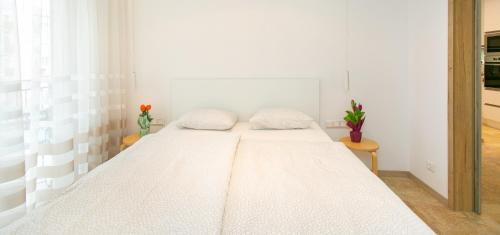 Bett in einem weißen Zimmer mit zwei Kissen darauf in der Unterkunft Mentha Apartman Szeged in Szeged