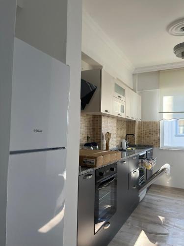 a kitchen with stainless steel appliances and white cabinets at Merkezi Hijyenik 3+1 Daire in Antalya
