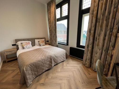 a bedroom with a bed and two windows at Boutique Hotel de Kade Zaandam-Amsterdam in Zaandam