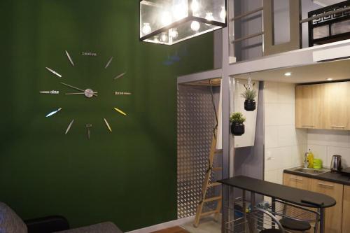 a clock on a green wall in a kitchen at Apartament Zielony Legionów 90 in Łódź