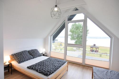 a bedroom with a bed and a large window at Domki U Zbyszka nad jeziorem z balią ogrodową! in Kiedrowice