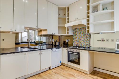 a large kitchen with white cabinets and appliances at Care Property London- Apartments in London