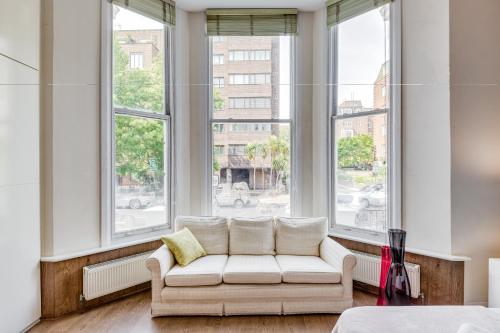 a white couch sitting in a room with windows at Care Property London- Apartments in London