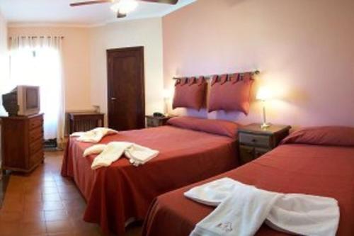 a hotel room with two beds and a television at Hosteria Zure-Echea in Valle Hermoso