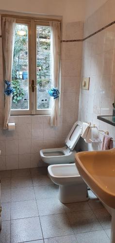 łazienka z 2 toaletami, umywalką i oknem w obiekcie L For Lake w mieście Mandello del Lario