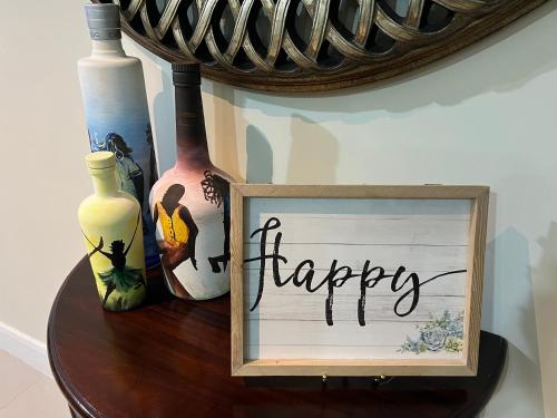 a sign that says happy sitting on a table with vases at Serenity Get Away in Lucea