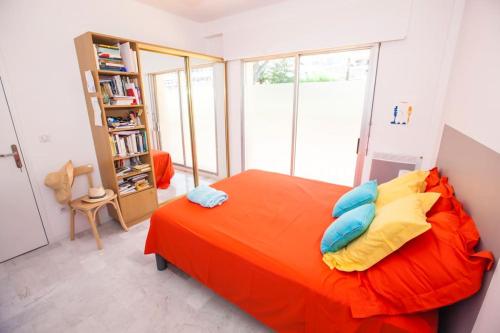 a bedroom with an orange bed and a book shelf at French Riviera: Seafront apt & pool near Monaco in Roquebrune-Cap-Martin