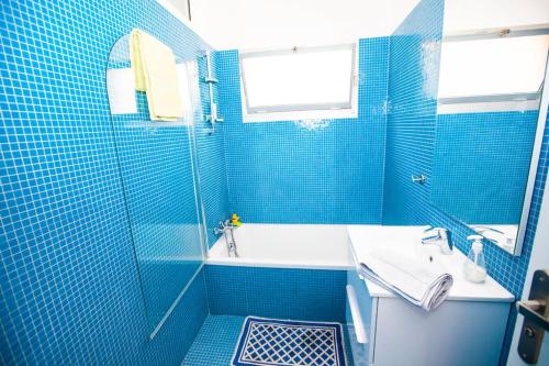 La salle de bains est pourvue de carrelage bleu, d'une baignoire et d'un lavabo. dans l'établissement French Riviera: Seafront apt & pool near Monaco, à Roquebrune-Cap-Martin