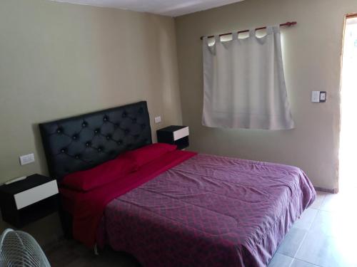 a bedroom with a bed with a purple comforter and a window at Hotel Bates in Villa General Belgrano