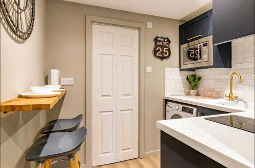 a kitchen with a white door and two black stools at The Hideaway by the sea - free parking in Brighton & Hove