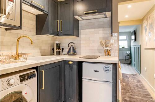 a kitchen with black cabinets and a white dishwasher at The Hideaway by the sea - free parking in Brighton & Hove