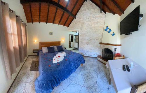 a bedroom with a bed with a blue comforter and a fireplace at Pousada Dona Ana in Monte Verde