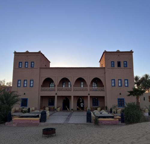 a large building with tables in front of it at Kanz Erremal in Merzouga