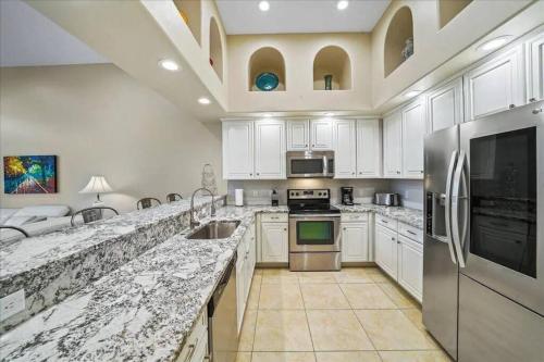 a large kitchen with white cabinets and stainless steel appliances at Beachside, 5 Bedroom Exclusive Home in Indian Harbour Beach