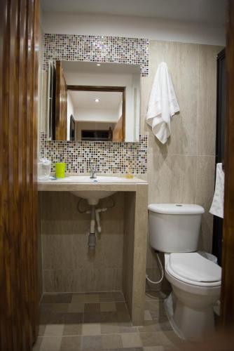 a bathroom with a toilet and a sink and a mirror at Hotel San Antonio del Cerro in Pereira