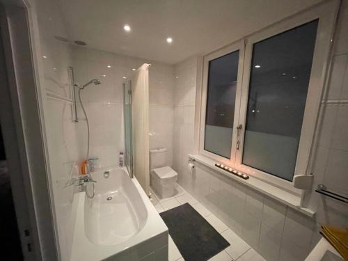 Baño blanco con bañera y lavamanos en Modern 1BR house near Heysel, Expo, Palais 12, Atomium, UZVUB et stade Roi Baudouin, en Wemmel