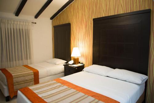 a hotel room with two beds and a lamp at Hotel San Antonio del Cerro in Pereira