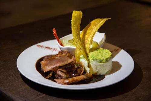 a white plate with food on a wooden table at Hotel San Antonio del Cerro in Pereira