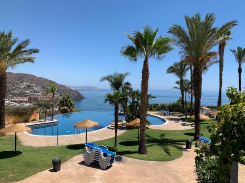 een uitzicht op een resort met palmbomen en een zwembad bij Adosado con piscina a 5 minutos de la playa in Almuñécar